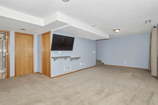 unfurnished living room with light colored carpet, visible vents, stairway, a textured ceiling, and baseboards