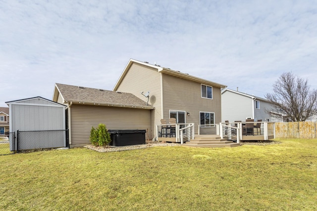 rear view of house featuring fence, a deck, and a lawn