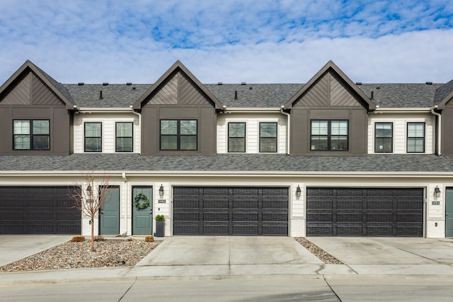 townhome / multi-family property featuring a garage, driveway, and a shingled roof