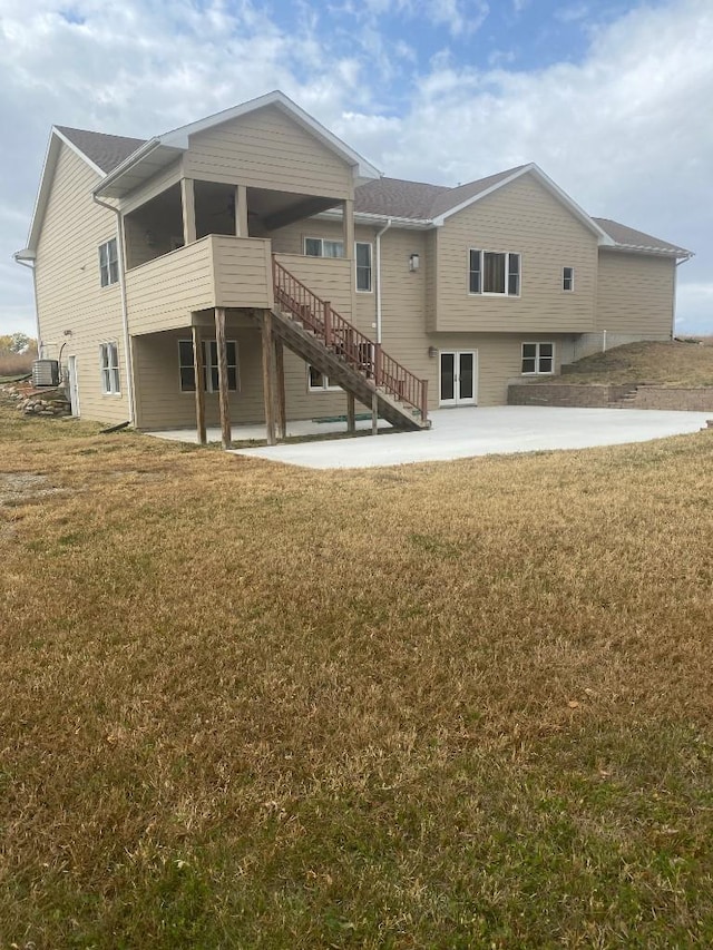 rear view of property featuring a sunroom, a patio area, a yard, and stairway