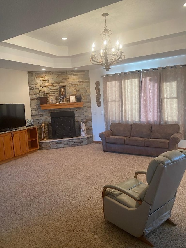 living area with carpet floors, a fireplace, a tray ceiling, and a notable chandelier