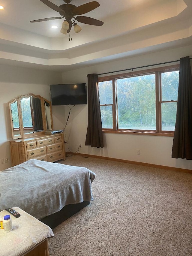 carpeted bedroom with multiple windows, baseboards, a raised ceiling, and recessed lighting