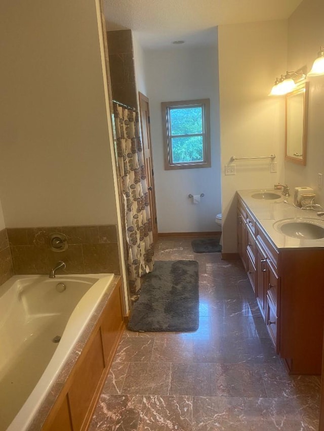 full bath with toilet, double vanity, a sink, and a bath