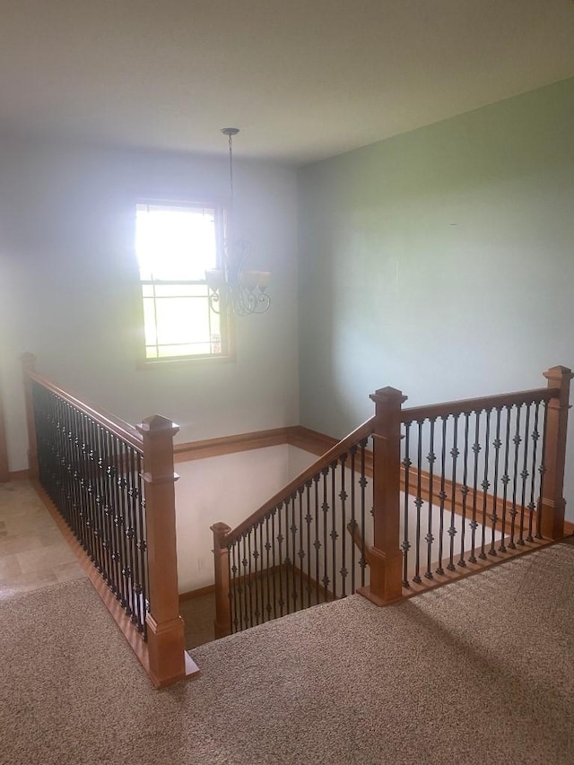 stairway featuring carpet floors and an inviting chandelier