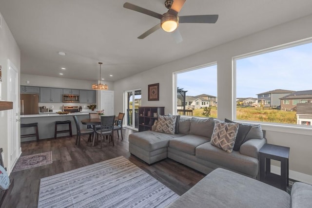 living room with dark wood-style flooring, recessed lighting, a residential view, baseboards, and ceiling fan with notable chandelier