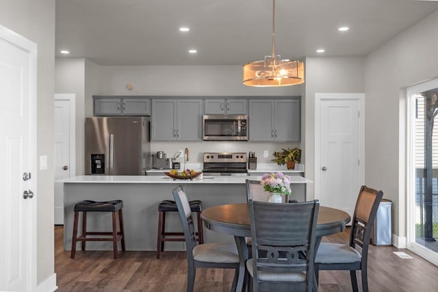 kitchen featuring gray cabinetry, stainless steel appliances, light countertops, and pendant lighting