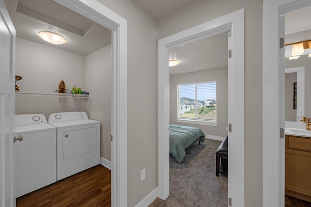 laundry room featuring dark wood-style floors, a sink, laundry area, independent washer and dryer, and baseboards