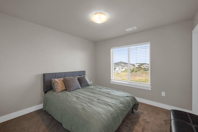 bedroom with dark colored carpet, visible vents, and baseboards