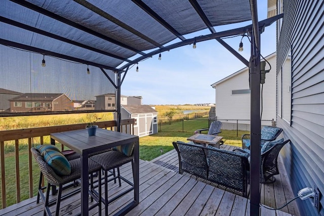 wooden deck featuring an outbuilding, a lawn, outdoor dining space, fence, and a shed