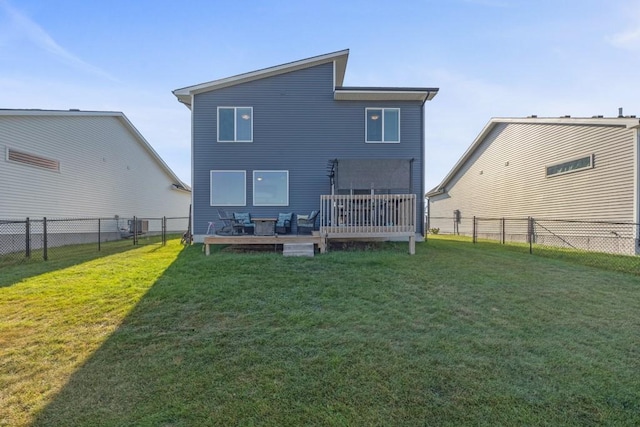 back of property with a lawn, a wooden deck, and a fenced backyard