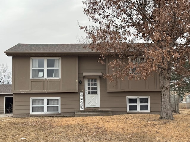 split foyer home with roof with shingles and a front lawn