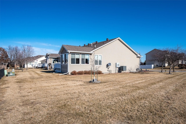 rear view of property featuring a residential view, cooling unit, and a lawn