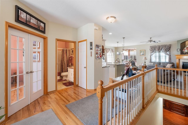 hall featuring a sink, an upstairs landing, baseboards, french doors, and light wood finished floors