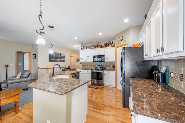 kitchen featuring light wood-style flooring, a kitchen island with sink, white cabinets, hanging light fixtures, and black appliances