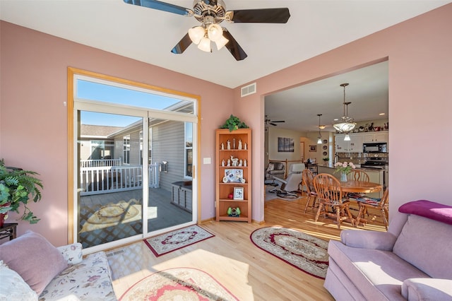 living room with ceiling fan, light wood-type flooring, and visible vents