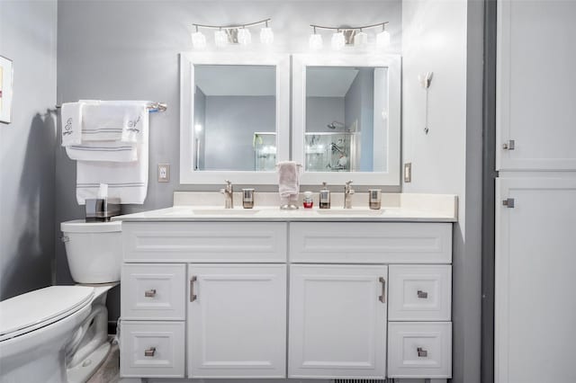 full bathroom featuring a shower with shower door, a sink, toilet, and double vanity