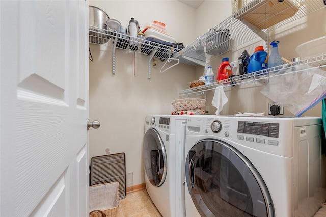 clothes washing area with light tile patterned floors, laundry area, independent washer and dryer, and baseboards