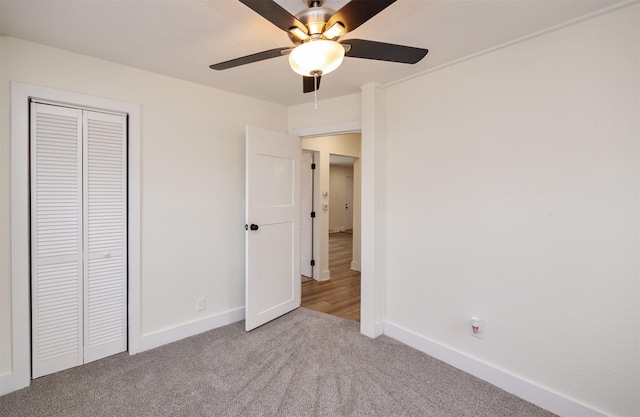 unfurnished bedroom featuring carpet, baseboards, ceiling fan, and a closet