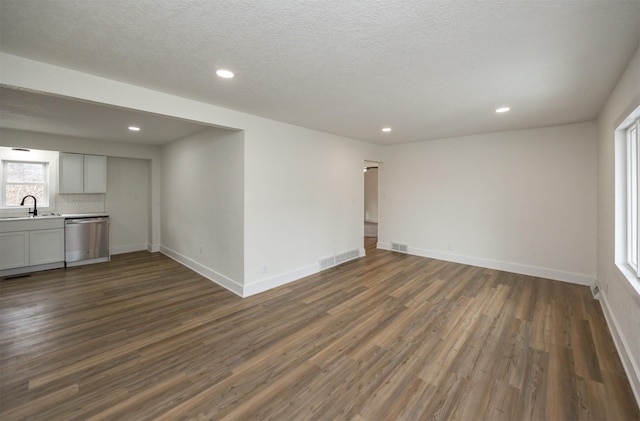 unfurnished room with baseboards, visible vents, dark wood-type flooring, and a sink