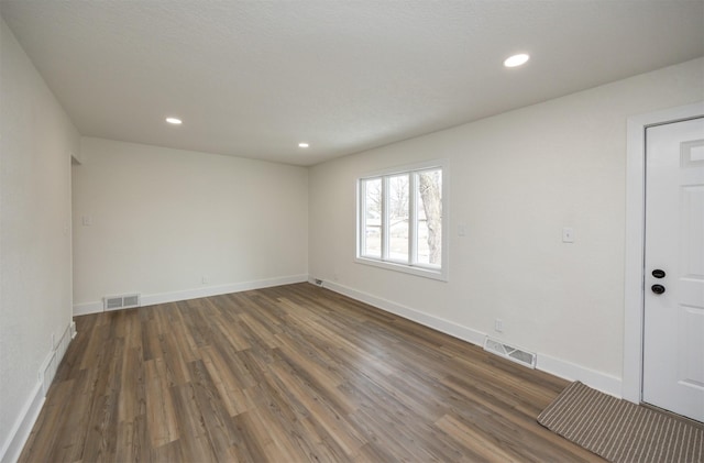 empty room featuring wood finished floors, visible vents, and recessed lighting