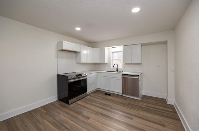 kitchen featuring dark wood-style floors, stainless steel appliances, visible vents, backsplash, and a sink