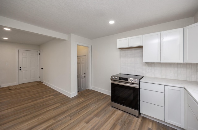 kitchen featuring light countertops, backsplash, stainless steel electric range, and wood finished floors