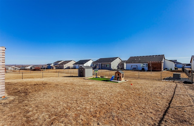 view of yard with a playground, a fenced backyard, an outdoor structure, a residential view, and a storage unit