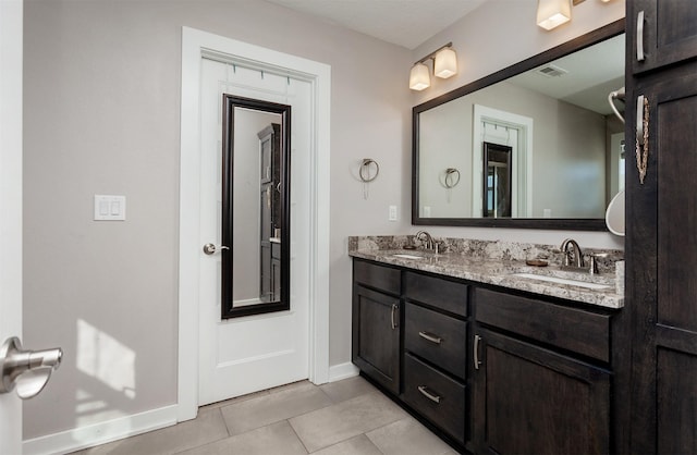 bathroom featuring tile patterned flooring, a sink, baseboards, and double vanity