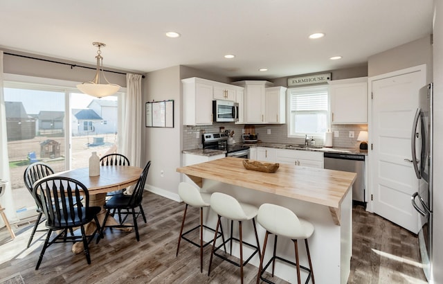 kitchen with appliances with stainless steel finishes, a center island, white cabinets, and hanging light fixtures