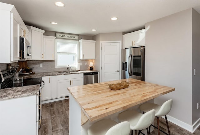 kitchen with a breakfast bar, white cabinetry, stainless steel appliances, and a center island