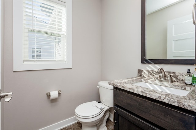 half bathroom with toilet, baseboards, and vanity