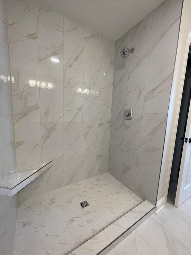 bathroom featuring marble finish floor and tiled shower