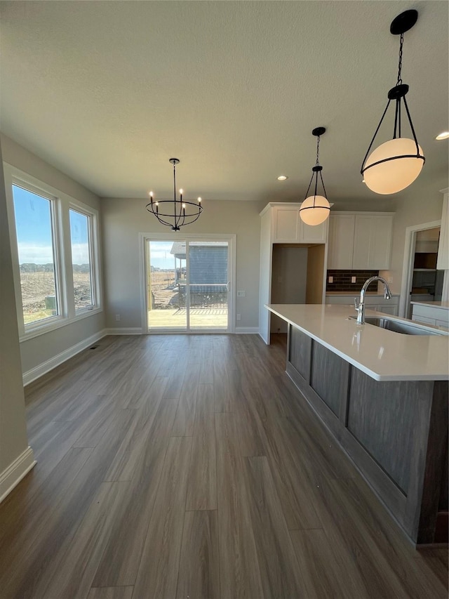 kitchen featuring white cabinets, dark wood finished floors, light countertops, and a sink