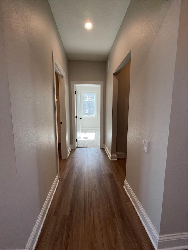 corridor featuring baseboards and dark wood finished floors