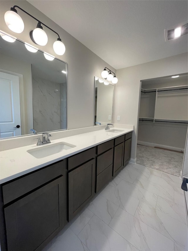 full bathroom with marble finish floor, visible vents, and a sink