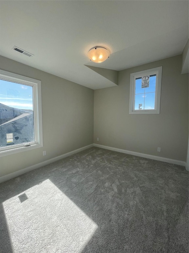 spare room with carpet flooring, visible vents, and baseboards