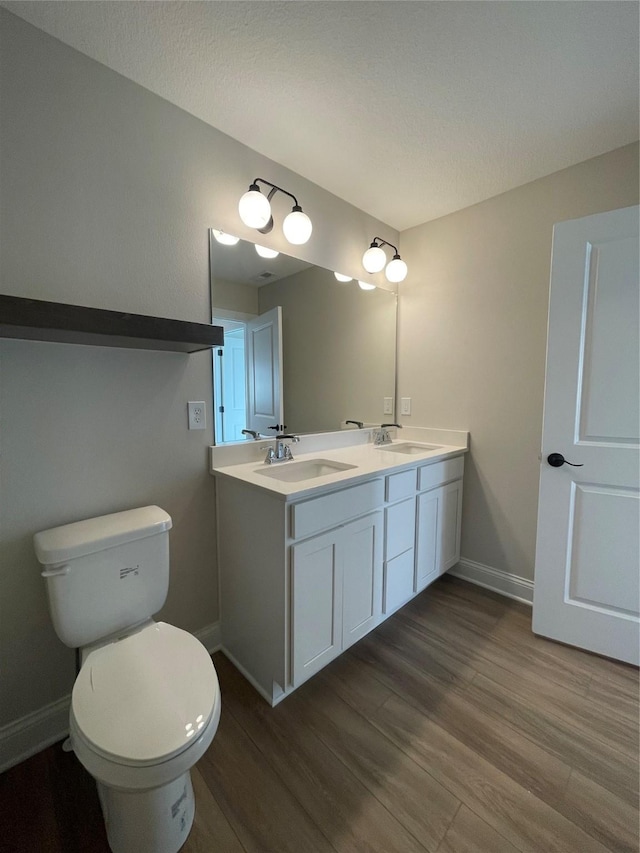 bathroom featuring wood finished floors, a sink, toilet, and baseboards