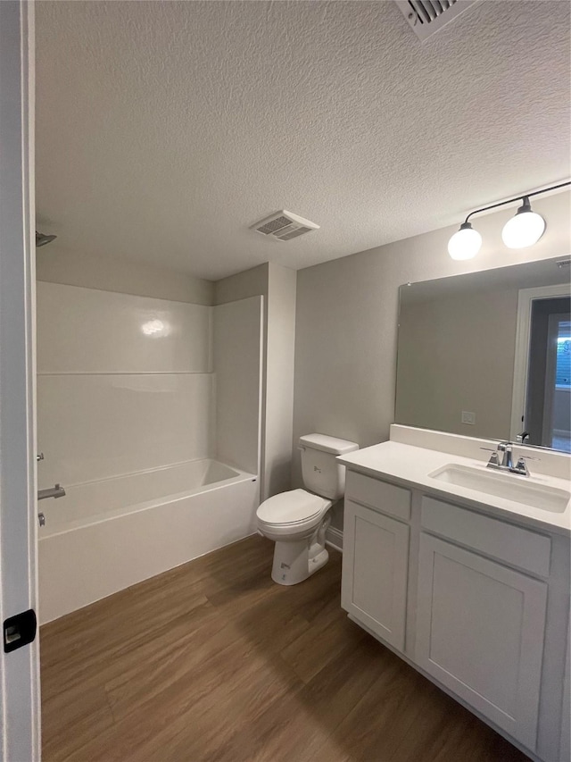 full bathroom featuring visible vents, toilet, a textured ceiling, vanity, and wood finished floors