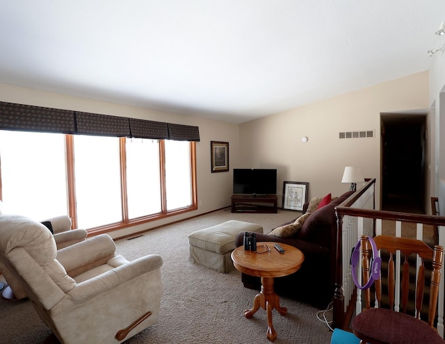 carpeted living room with visible vents and lofted ceiling