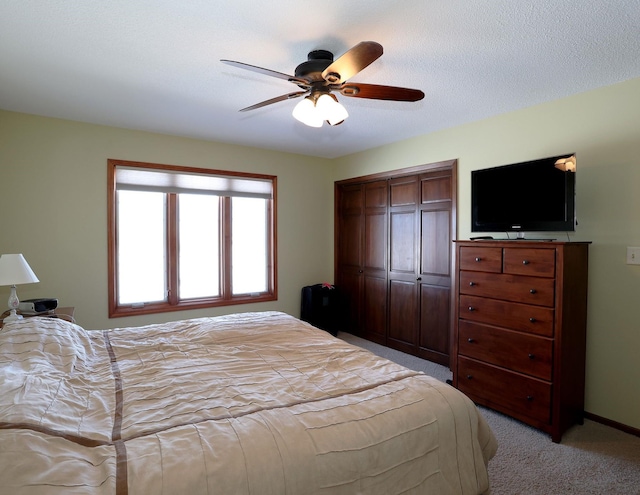 bedroom with a ceiling fan, light colored carpet, a closet, and a textured ceiling