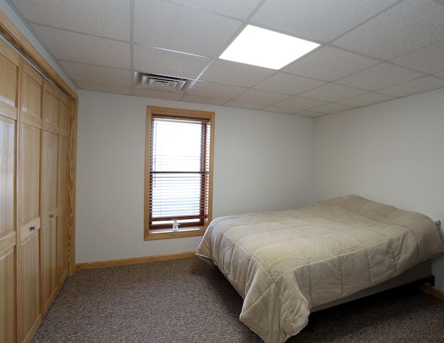 bedroom with visible vents, a drop ceiling, a closet, carpet floors, and baseboards