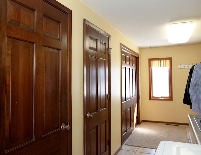 interior space featuring light tile patterned floors, visible vents, light carpet, and baseboards