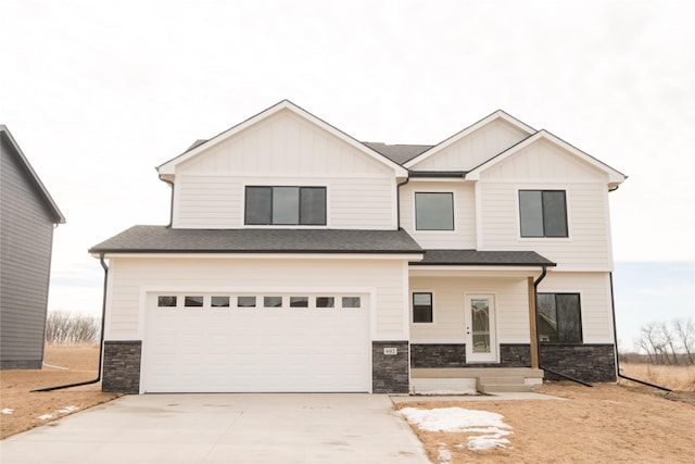 view of front of house featuring a shingled roof, an attached garage, board and batten siding, stone siding, and driveway