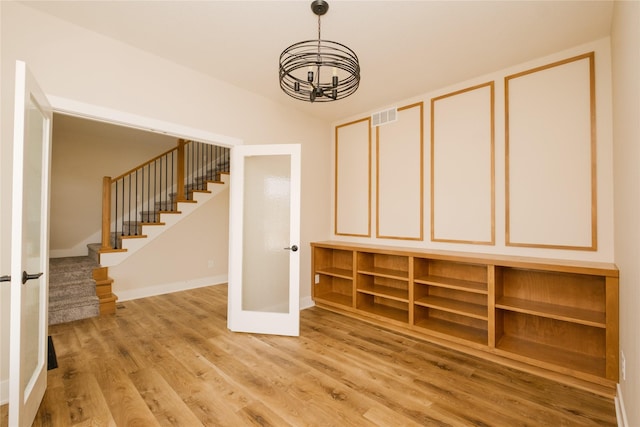 interior space with visible vents, vaulted ceiling, wood finished floors, baseboards, and stairs