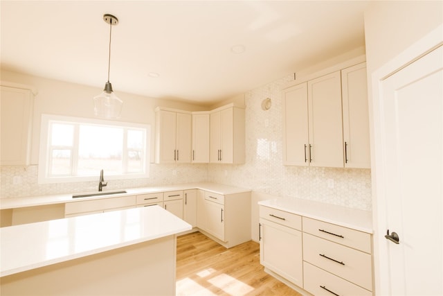 kitchen featuring light countertops, a sink, hanging light fixtures, and white cabinetry