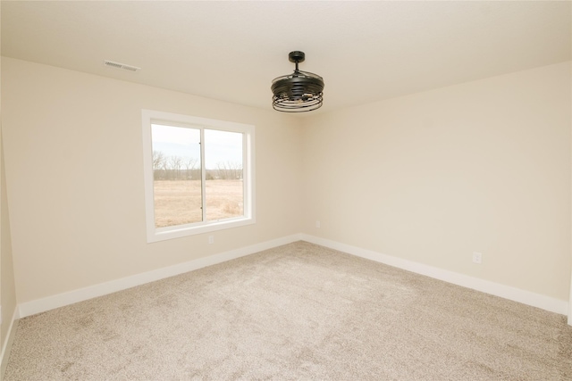 empty room with baseboards, visible vents, and carpet flooring