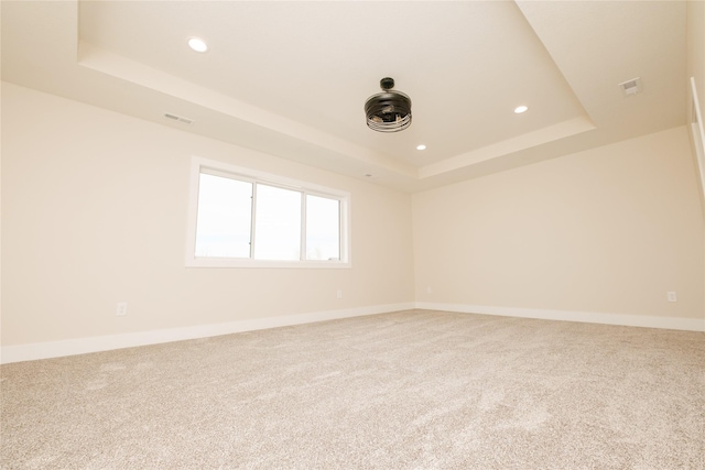 carpeted spare room featuring recessed lighting, a raised ceiling, visible vents, and baseboards