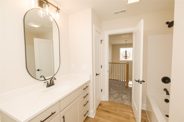 full bath featuring vanity, bathtub / shower combination, wood finished floors, and visible vents