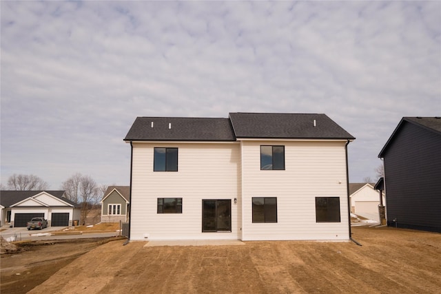 back of house with a garage and roof with shingles