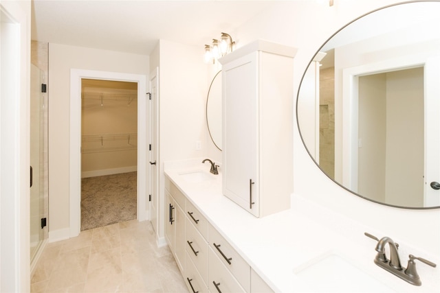 full bath with a walk in closet, a sink, a shower stall, and double vanity